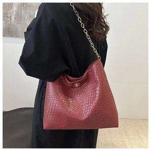 Détail du sac cabas matelassé bordeaux avec chaîne dorée porté par un mannequin