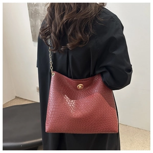 Détail du sac hobo bordeaux tressé avec bandoulière chaîne dorée et fermoir pivotant