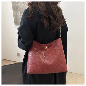 Sac cabas rouge brique à texture croco et fermoir doré porté par un mannequin en gros plan
