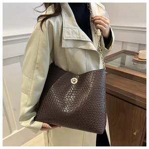 Détail du sac fourre-tout en cuir marron tissé avec fermoir doré et bandoulière chaîne
