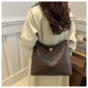 Détail d'un sac à bandoulière marron foncé texturé avec fermoir doré et bandoulière chaîne