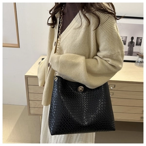 Détail d'un sac cabas noir à motif serpent avec chaîne dorée sur un mannequin
