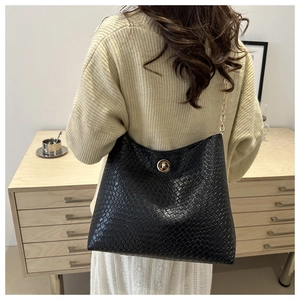 Détail d'un sac bandoulière noir tressé avec fermoir doré et bandoulière chaîne et cuir