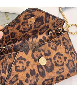 Detailed close-up of the leopard print envelope bag featuring a gold magnetic snap buckle