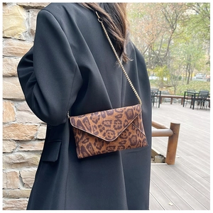 Detail of leopard print envelope bag with gold chain strap on a black blazer