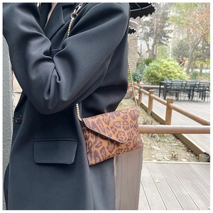 Street style view of leopard print envelope bag with gold chain strap on black blazer