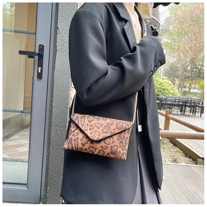Chic leopard print envelope crossbody bag with gold chain strap on a black blazer