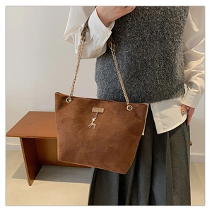 Detail of dark brown matte tote bag featuring golden deer charm and elegant chain strap