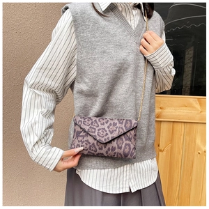 Leopard print envelope clutch bag with elegant gold chain strap worn by a fashion model