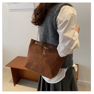 Detail of dark brown matte shoulder bag with gold chain strap and deer pendant on model