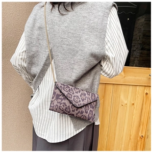 Detailed close-up of leopard print envelope crossbody bag with a gold chain strap
