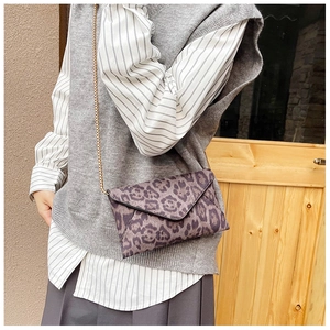Chic leopard print envelope crossbody bag with a delicate gold chain strap on a model