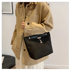 Close-up of black suede shoulder bag featuring a golden deer pendant and chain strap