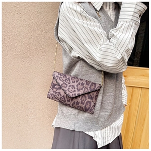 Close-up of leopard print envelope clutch featuring a gold chain and pointed flap design