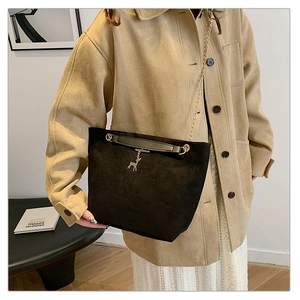 Detail of black suede bucket bag featuring golden chain and metal deer charm