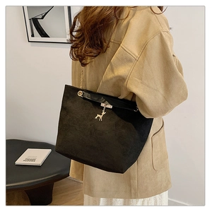 Detail of black suede tote bag featuring a golden deer charm and hybrid chain strap