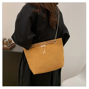 Detail of mustard yellow suede shoulder bag with golden chain and deer pendant