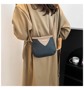 Détail du petit sac bandoulière bicolore porté sur un trench-coat kaki avec boucle dorée