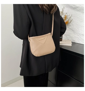 Détail du sac beige bandoulière avec texture grainée et barre dorée sur rabat en V