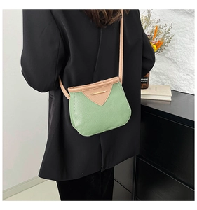 Gros plan sur la texture du cuir et le détail métallique d'un sac bandoulière vert