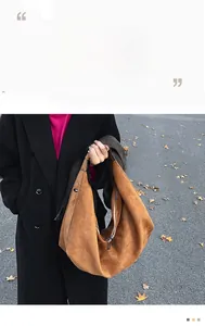 Detailed view of brown suede shoulder bag with dual metal zippers and spacious interior
