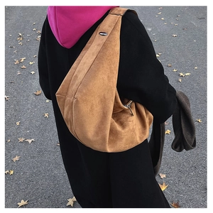 Detail of camel suede tote bag with wide shoulder strap and metal buckle closure