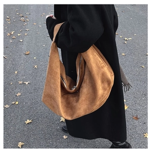 Detail of the brown suede tote bag with silver zipper in an autumn street setting