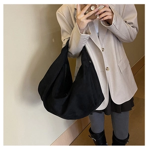 Detail of a large black slouchy suede hobo bag shown worn over the shoulder for commute