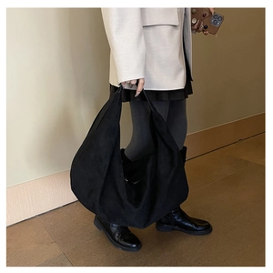 Detail of a large black suede tote bag with a minimalist slouchy hobo design and wide strap