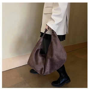 Close-up of a large coffee brown suede tote bag worn on shoulder in minimalist hallway