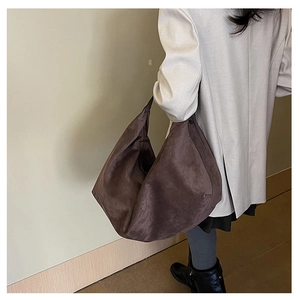Brown suede tote bag side view on shoulder showing its large capacity and drape