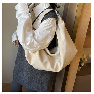 Detail of a large beige canvas hobo bag showing its crescent shape and woven texture