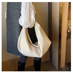 Detail of cream pleated tote bag showing the wide strap and soft canvas texture on shoulder
