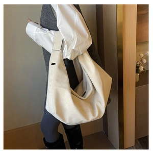 Detail of a beige oversized pleated hobo bag with wide shoulder strap on a model