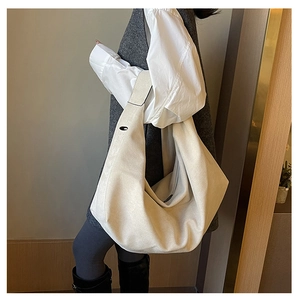 Off-white large capacity tote bag shown on shoulder in a minimalist indoor setting