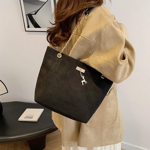 Retro black matte tote bag with gold chain and deer charm in a minimalist setting