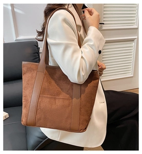 Detail of vintage brown suede tote bag with leather trim and large capacity on a model
