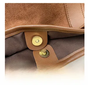 Detail of high-quality golden magnetic closure and suede lining on brown leather tote
