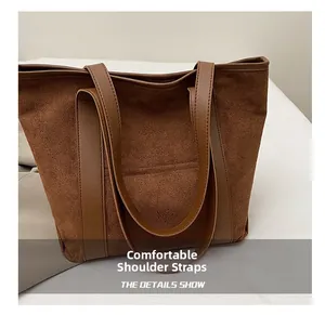 Close-up of brown suede bucket bag featuring smooth leather dual shoulder straps and texture