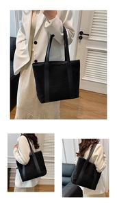 Detailed view of spacious black minimalist tote bag with thick shoulder straps and matte texture
