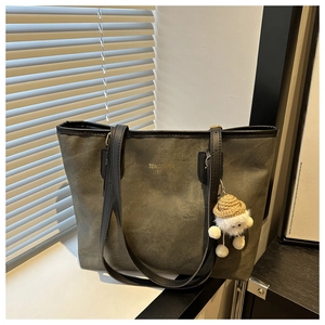 Olive green tote bag detail with golden text and cute plush doll charm accessory