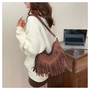 Dettaglio di una borsa hobo in pelle scamosciata marrone scuro con nappe in stile bohémien