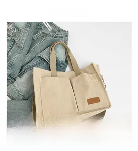 Detail of off-white corduroy tote bag featuring two front pockets and a fashion leather label