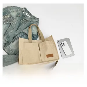 Detail of beige corduroy tote bag with dual front pockets and adjustable strap for women