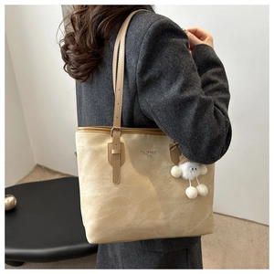 Close-up of beige suede tote bag with adjustable straps and cute plush pendant