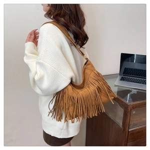 Dettaglio della borsa a spalla marrone in finta pelle scamosciata con lunghe frange su modella