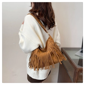 Close-up of brown suede hobo bag with long tassels on a model in a white knit sweater