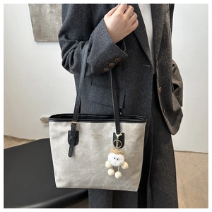 Detail of grey tote bag with contrast black strap and white plush sheep charm