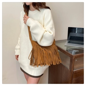 Dettaglio ravvicinato della borsa marrone scamosciata con nappe e texture boho
