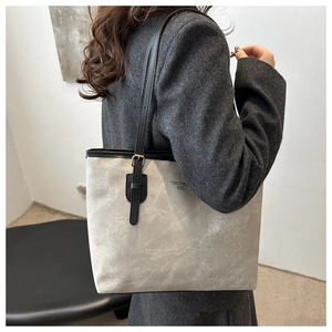Detail view of grey matte tote bag with thin black straps and golden adjustable buckles